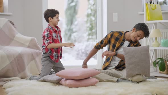 Laughing Positive Brothers Fighting Pillows in Slow Motion and Giving Highfive Indoors alt