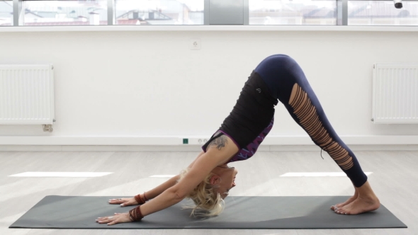 Woman Doing Yoga Exercise on Mat in Gym alt