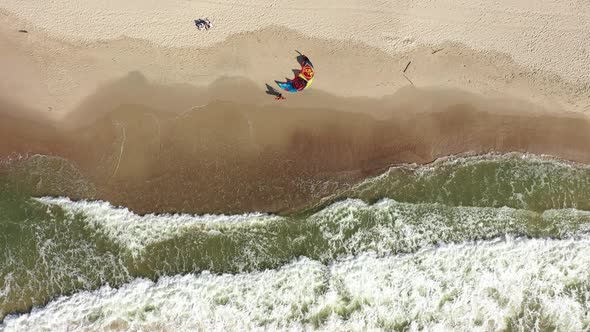AERIAL: Top View Shot of Surfer Coming to His Wind Kite Placed on a Sandy Beach in Nida