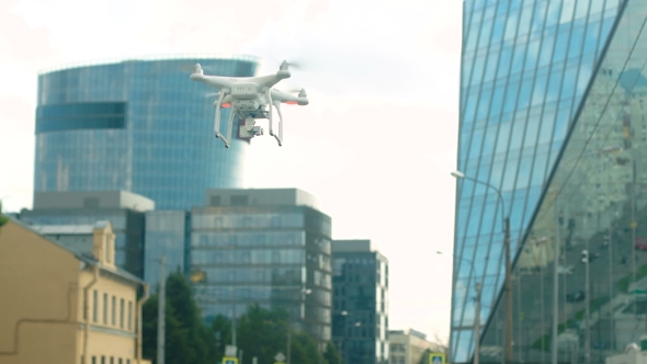 A Radio-controlled Quadcopter Hovers Over a Street In The City
