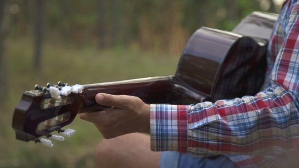 Young Man Playing Guitar In City Park On Sun Rays Background