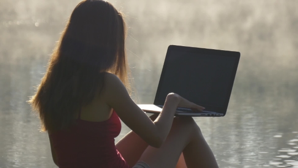 Woman Typing On Computer At The Lake On Sunrise