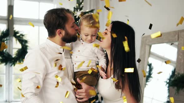 Young Family with Their Cute Little Toddler Being Excited with Sparkling Confetti Falling All Around alt