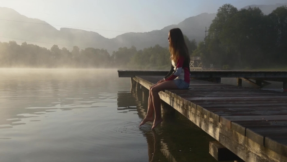Pensive Woman On Pier Of Mountain Lake