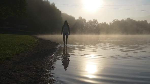 Silhouete Of Woman Walking In Shining Water