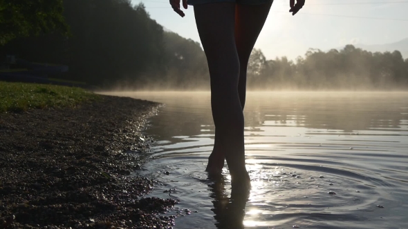 Silhouette Of Female Legs Walking In The Water