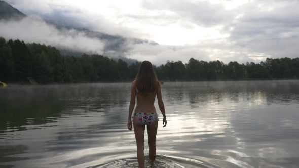 Woman Walks Into The Water And Swims In a Lake