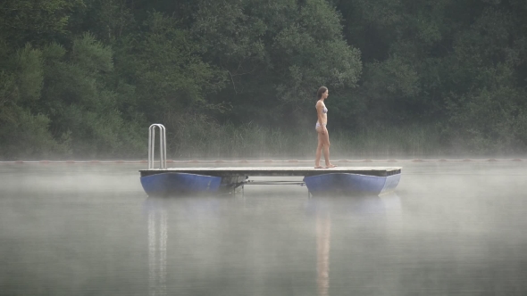 Woman Walks On Pontoon In Lake In Morning Mist