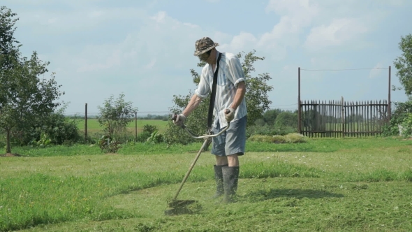 Gardener Cuts The Grass With Lawn String Trimmer