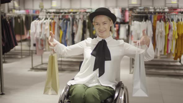 Paraplegic Woman Posing with Shopping Bags in Clothing Store alt