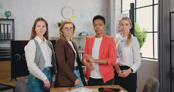 business women are standing with crossed arms smiling looking at camera, posing in modern office alt