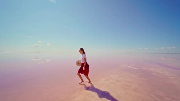 Happy Woman in Red Skirt Running Enjoying Bright Pink Salt Lake with Blue Sky alt