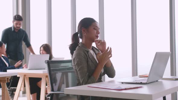 A young company employee is feeling tired while sitting at work for a long time. alt