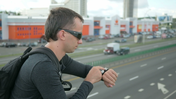 Outdoor Portrait Of Modern Young Man With Smart Watch In The Street. The Man In Glasses
