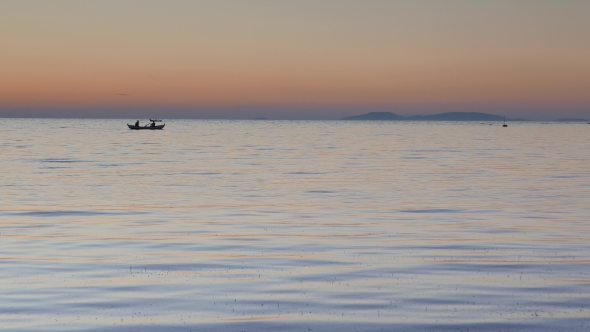 Calm Sea With a Silhouetted Rowing Boat at Sunset. 