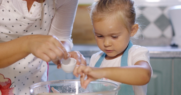 Cute Little Girl Adding Salt To a Baking Mixture alt