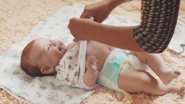 Mother Undress Smiling Adorable Baby On Table. Communication. Motherhood. Love alt