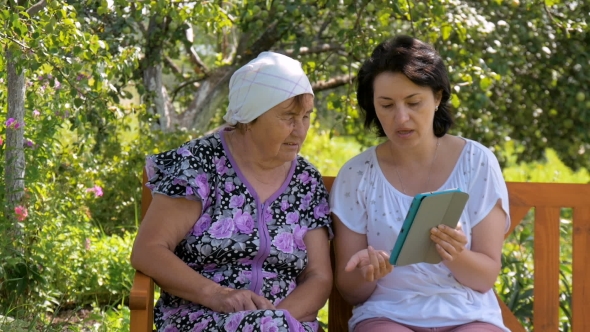 Young Woman Shows Her Elderly Mother How To Use The Tablet.