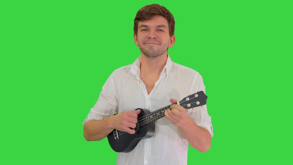 Smiling Young Man Playing Ukulele Looking Into Camera Green Screen Chroma Key alt