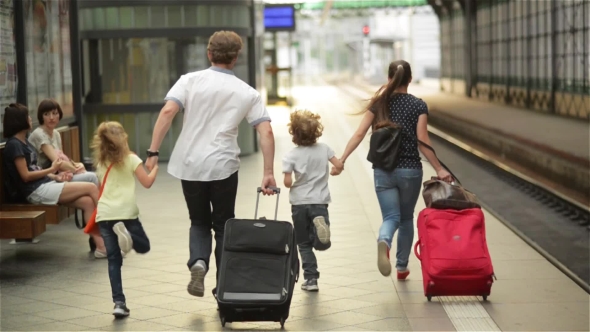 Young Family Of Two Spouses, Son And Daughter, Running To Catch The Train Before It Leaves The alt