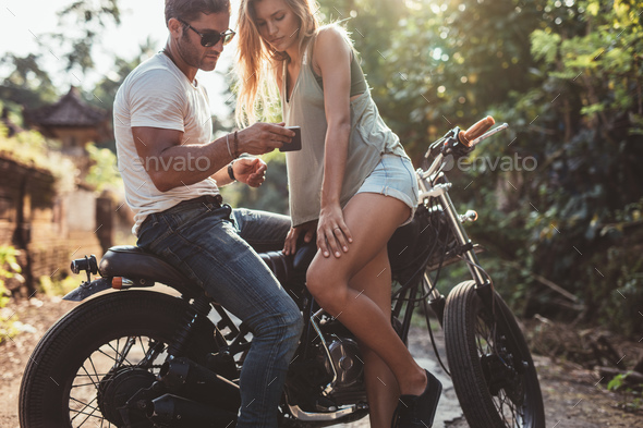 Couple outside on bike looking at mobile phone - Stock Photo - Images