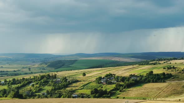 Tilt Up Aerial View of Thick Clouds Floating on Sky Over Green Hills with Agricultural Fields in alt