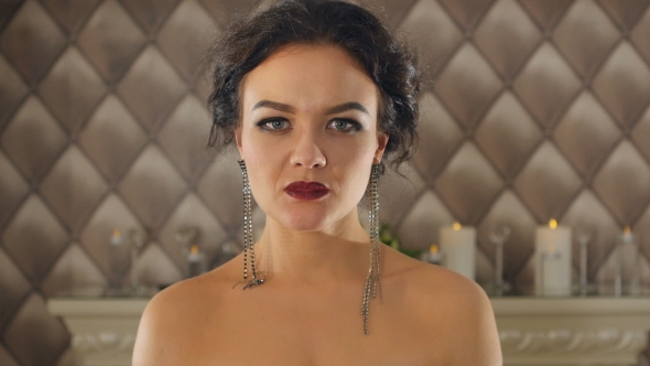 Portrait Of a Brunette Woman With Big Lips And Long Earrings Looks At Camera alt