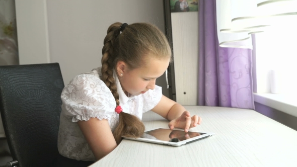 Schoolgirl Uses a Digital Tablet Computer At Home alt