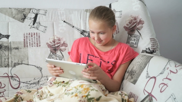 Child Lying On The Bed With a Digital Tablet