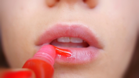 Woman Paints Her  Sexy Lips With Lipstick In . Bright Red
