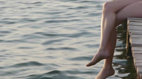 Young woman sitting on jetty, portrait alt