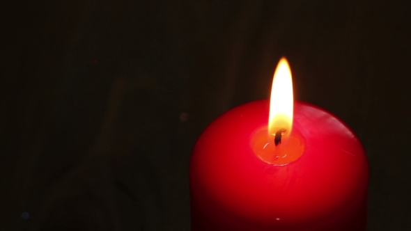 Burning Candle In Red Wax On a Dark Background.