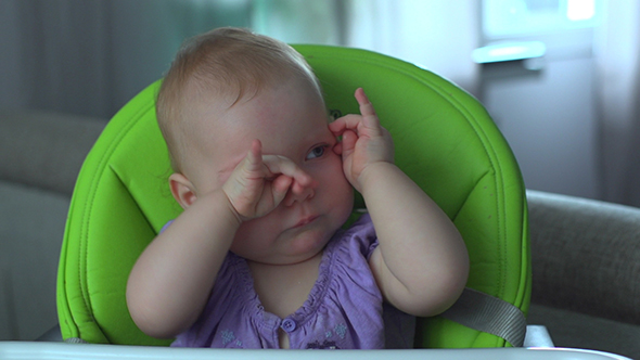 Baby Girl Sitting on Chair and Rubs Hes Eyes