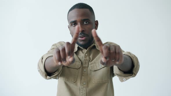 Slow Motion Portrait of Confident AfroAmerican Man Wagging Fingers and Saying NO on White Background alt