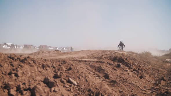 Skilled motocross rider on a sandy track, performing stunts on motorcycles, moto festival.