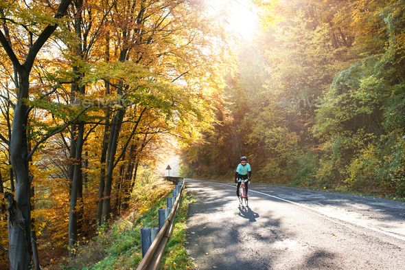 Young sportsman riding bicycle outside in sunny autumn nature