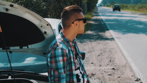 Boy Stay At Broken Car At Road. Hitchhiking. Wait For Help. Put Off Sunglasses alt