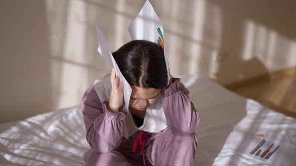 Overwhelmed Exhausted Little Woman with Graphs Sitting on Bed at Home Holding Head in Hands Sighing alt