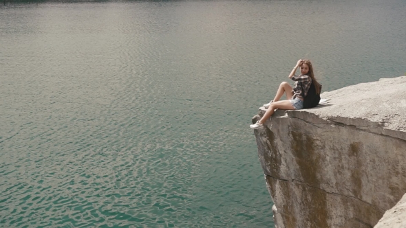Young Active Backpacker Girl Relaxes By Resting On Mountain Rock Upon Large Water Surface Of