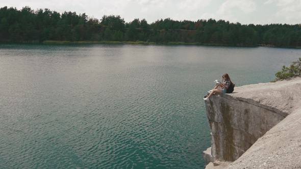 Young Active Backpacker Girl Relaxes By Resting On Mountain Rock Upon Large Water Surface Of