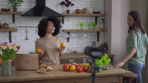 Confident Young African American and Asian Women Recording Healthy Food Video Blog on Camera in alt