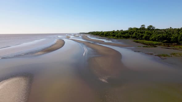 Slow wide forward aerial shot of sand banks by coast of La Plata River alt