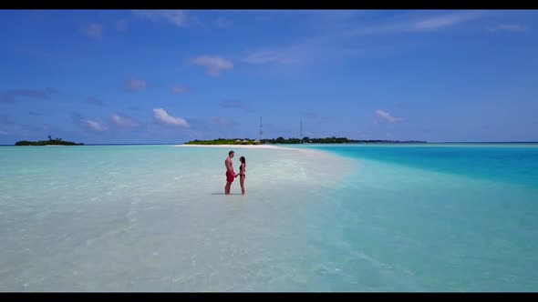 Young couple tanning on perfect lagoon beach journey by blue green lagoon with white sand background alt