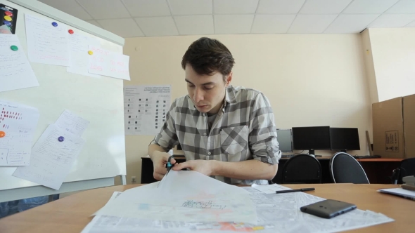 Man Carefully Cuts Carbon Paper With Black Layout Of Building On It.