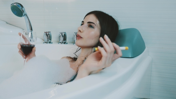 Girl Drink Red Wine In Bath Full Of Foam Smoking Electronic Cigarette