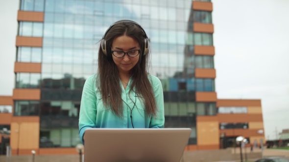 Young Beautiful Girl Sitting With a Laptop And Headphones