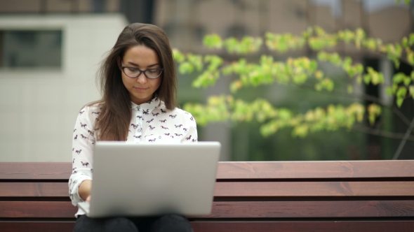 Elegant Young Woman Sitting With a Laptop Outdoors. Remote Work.