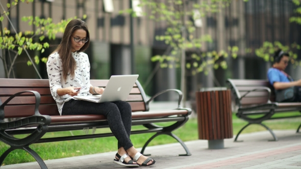 Beautiful Girl With a Laptop Sitting On The Street. Remote Work.