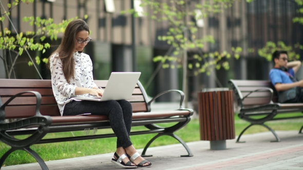 Elegant Young Woman Sitting With a Laptop Outdoors.