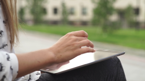 Women's Hands With The Black Tablet. Uncertain Woman Uses Touchscreen